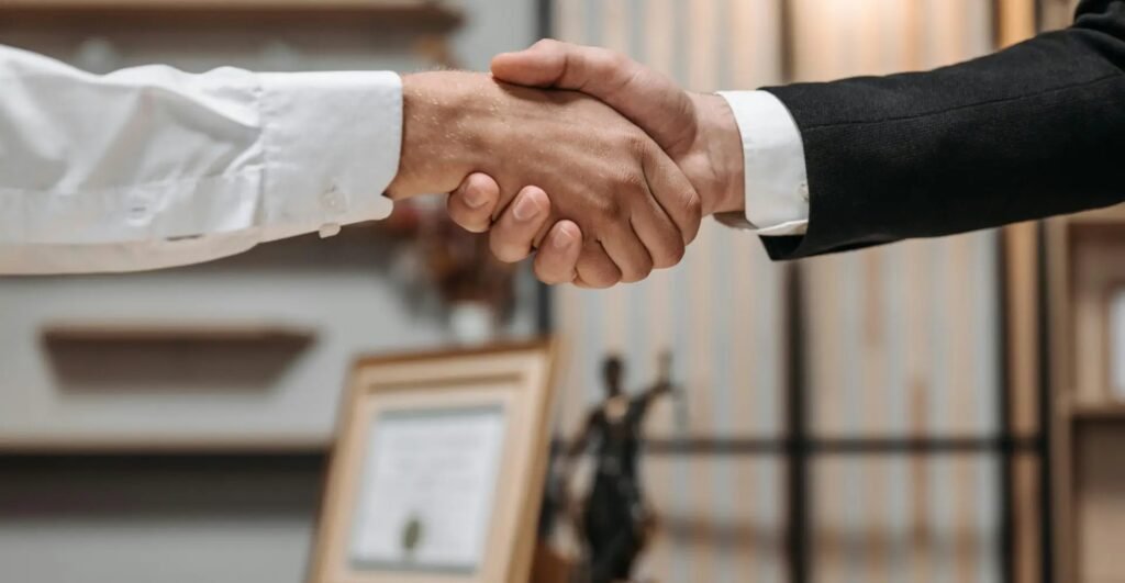 Close-up of a handshake between two professionals in a modern office setting, emphasizing partnership and agreement.